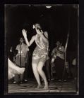 USO entertainment. Woman dancing with men behind her singing and playing guitar